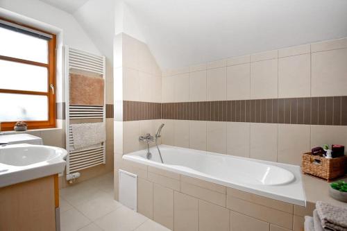 Baño blanco con bañera y lavamanos en Apartmán s terasou, en Říčky