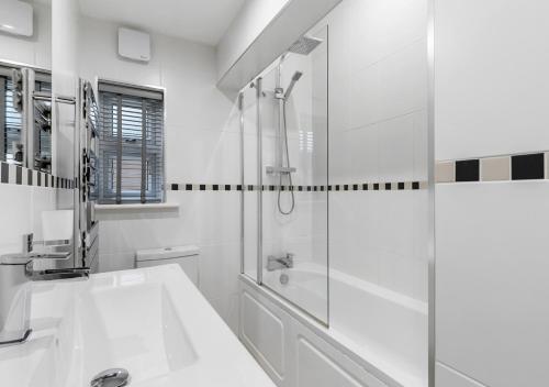 a white bathroom with a shower and a sink at Two Bed Flat in Bush Hill Park in Enfield
