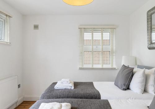 a white bedroom with a bed and a window at Two Bed Flat in Bush Hill Park in Enfield