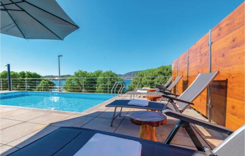 a patio with a pool and chairs and an umbrella at Nice Home In Kneze With Wifi in Pupnat