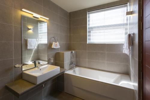 ein Badezimmer mit einer Badewanne, einem Waschbecken und einem Spiegel in der Unterkunft Niwahas Apartment Borella in Colombo
