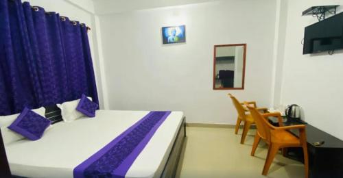 a bedroom with a bed with purple pillows and a table at Ocean Glass in Baga