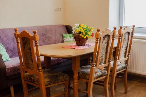 a wooden table with chairs and a vase of flowers on it at Gazdov dvor in Vavrišovo