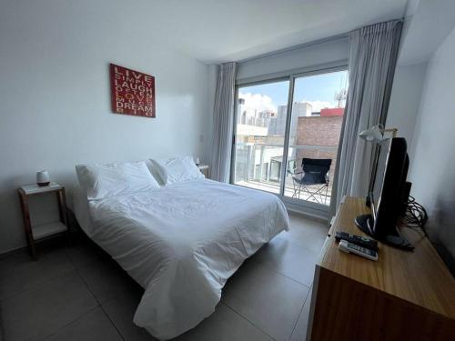 1 dormitorio con 1 cama, TV y ventana en Deluxe apartment in great location en Buenos Aires