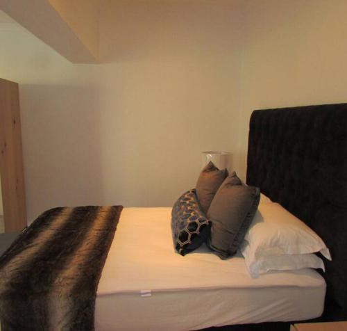 uma cama com várias almofadas em cima em Lovely 1-bedroom rental with a pool em Cidade do Cabo