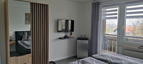 - une chambre avec un lit, une télévision et une fenêtre dans l'établissement Gästehaus Fechtig, à Hergensweiler