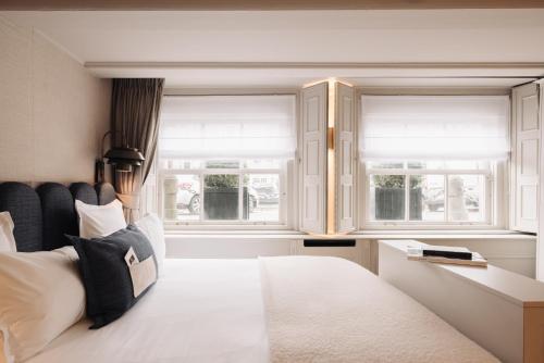 a bedroom with a white bed and two windows at Hotel 717 in Amsterdam