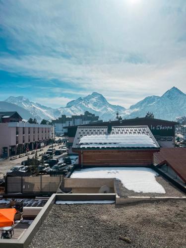 a building with snow on the roof with mountains in the background at Atmosphere Hotel in Les Deux Alpes