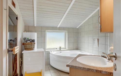 Baño blanco con bañera y lavamanos en Awesome Home In Askeby With 4 Bedrooms, Sauna And Wifi en Askeby