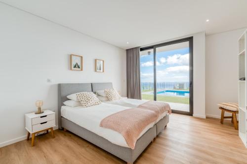 a bedroom with a bed and a large window at Vila Inanda in Ponta do Sol