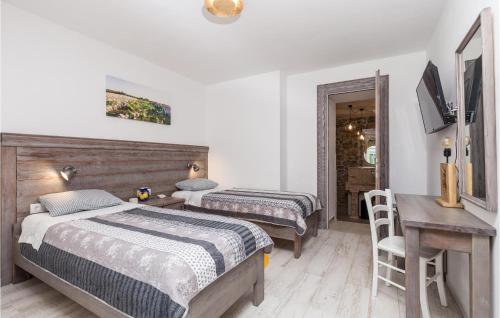 a bedroom with two beds and a table and a desk at Awesome Home In Kornic With Kitchen in Kornić