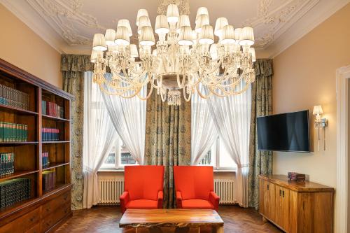 a living room with a chandelier and two red chairs at BHG Apartments Prague in Prague