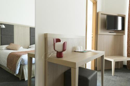 a hotel room with a bed and a desk with a tv at Hotel Casa Valdese Roma in Rome