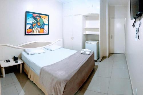 a small bedroom with a bed and a painting on the wall at Biss Inn Hotel in Goiânia