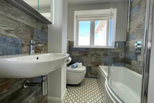 y baño con lavabo, bañera y aseo. en Luxury house with sea view Dorset, Inglaterra, Reino Unido en Radipole