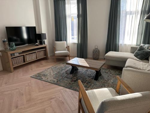 a living room with a couch and a tv at Casa de Schans - 6 persoons vakantiehuis in Landgraaf