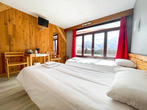a bedroom with two beds and a window with red curtains at Atmosphere Hotel in Les Deux Alpes