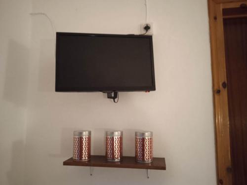a flat screen tv on a wall with three metal canisters at Villa Kaloudis Rooms in Agios Georgios
