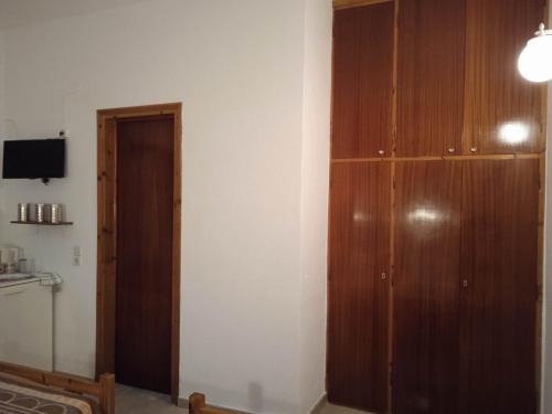 a room with a wooden cabinet and a television at Villa Kaloudis Rooms in Agios Georgios