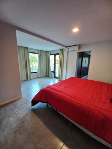 1 dormitorio con 1 cama roja en una habitación con ventanas en Cholas en Merlo