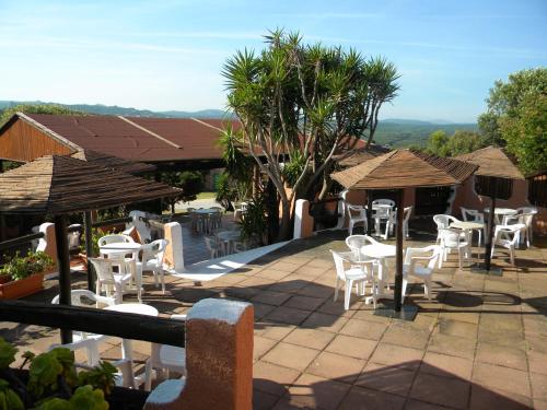 a patio with white chairs and tables and umbrellas at La Liccia - Camping&Village in Santa Teresa Gallura