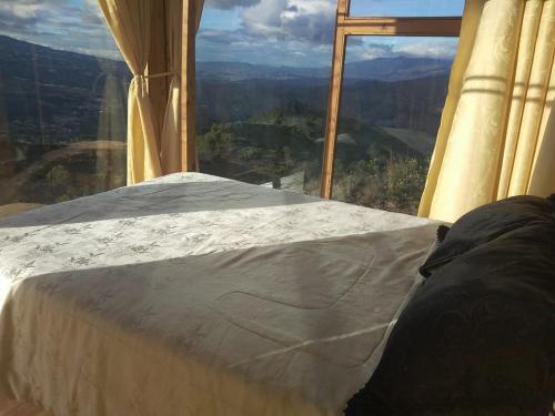 a bed in a room with a view of the mountains at Entre Rocas y Cristales in Ráquira