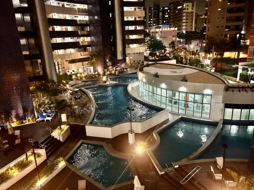 uma vista panorâmica de uma piscina numa cidade à noite em DN Apartamento no beach class ,VISTA MAR ,Fortaleza em Fortaleza