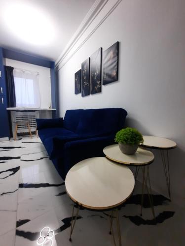 a living room with a blue couch and two tables at Flamingo Apartment1 Craiova self check-in in Craiova