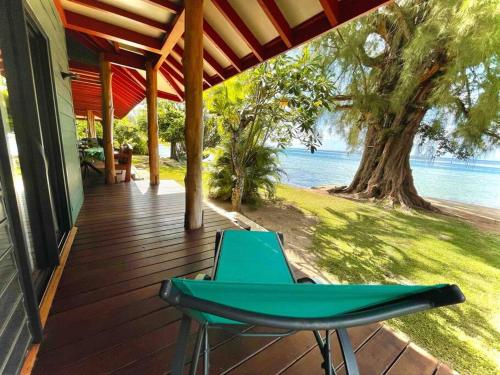 a green chair sitting on a porch next to the water at Turia's Beach Villa in Moorea