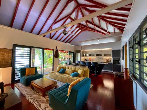 a living room with a couch and chairs and a kitchen at Turia's Beach Villa in Moorea