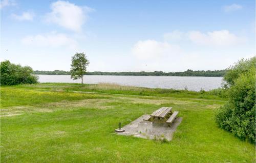 un banco sentado en el césped junto a un lago en Gorgeous Home In Ansager With Kitchen, en Ansager