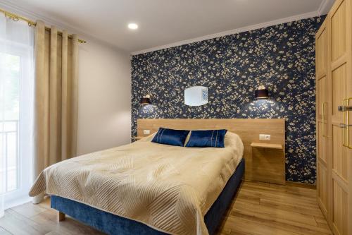 a bedroom with a bed with a blue accent wall at Apartamenty Pod Lipami in Kudowa-Zdrój