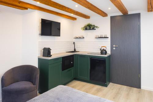 uma cozinha com armários verdes e uma porta preta em Stadtmauer-Apartments - Neue helle Studio Wohnung direkt an der historischen Stadtmauer em Nördlingen