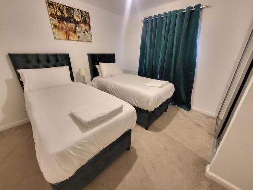 two beds in a small room with green curtains at Garland Apartment, Greenhithe 3 in Dartford