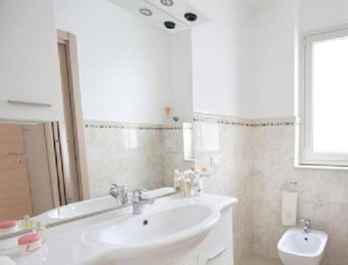 La salle de bains est pourvue d'un lavabo, d'une baignoire et d'un miroir. dans l'établissement Casa Vacanza Nina, à Pozzallo