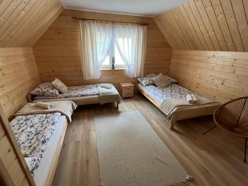 una habitación con tres camas en una casa de madera en Domki pod Grapą, en Trybsz