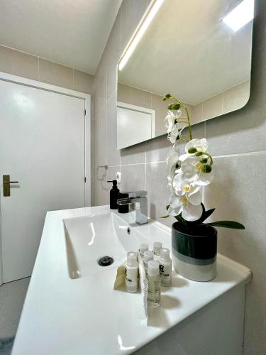 a bathroom sink with a vase of flowers on it at Funchal Lido View 1 in Funchal