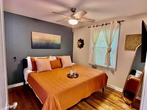 a bedroom with a bed with orange sheets and a ceiling fan at 9 Minutes From ATL Airport 2BD Home FREE PKNG in Atlanta