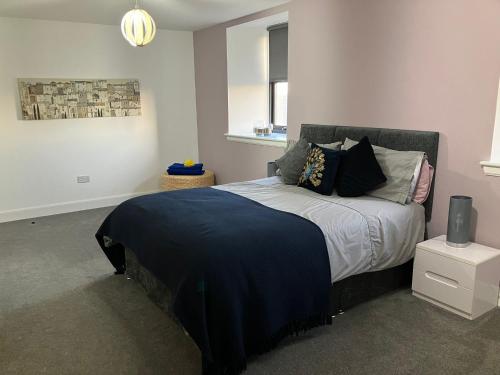 a bedroom with a bed with a blue blanket on it at Kirkview in Johnshaven