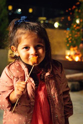 a little girl eating food on a stick at Hotel Le Renard - Campos do Jordao in Campos do Jordão