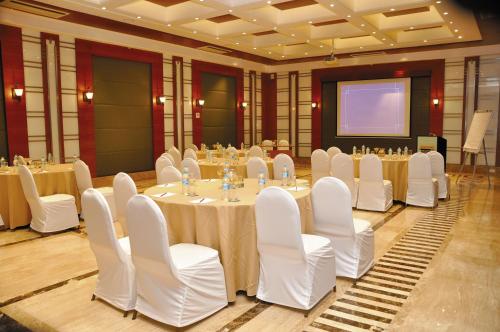 a conference room with tables and white chairs and a screen at Evershine Resort & Spa in Mahabaleshwar