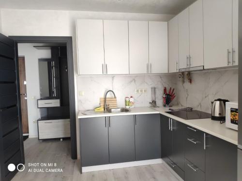 uma cozinha com armários brancos e um lavatório em Apartmets Domovik Вместительная трьохкомнатная квартира em Mukacheve