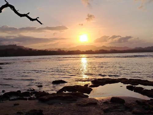 a sunset on the shore of a body of water at Terra NaturaMa - off grid living in the jungle in Punta Uva