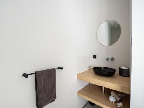 La salle de bains est pourvue d'un lavabo noir et d'un miroir. dans l'établissement Spacious holiday home in Aardenburg with terrace, à Aardenburg