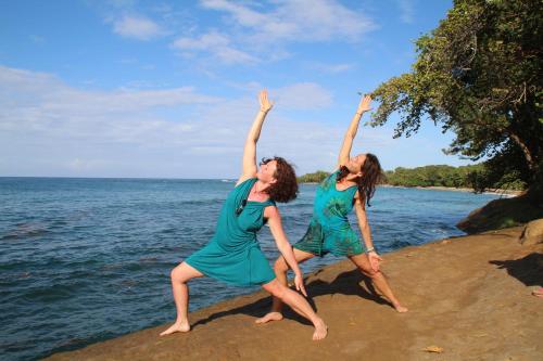 two women are jumping on the beach near the water at Terra NaturaMa - off grid living in the jungle in Punta Uva