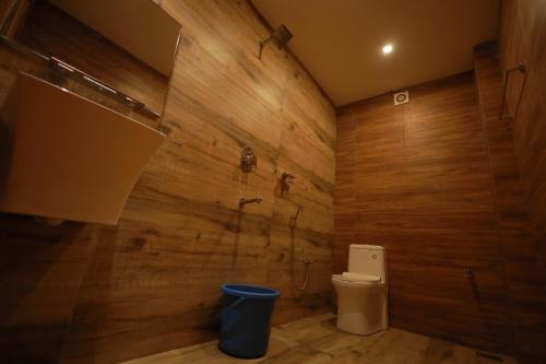 La salle de bains est pourvue de toilettes et d'un mur en bois. dans l'établissement HYDEPARK REGENCY, à Palakkad