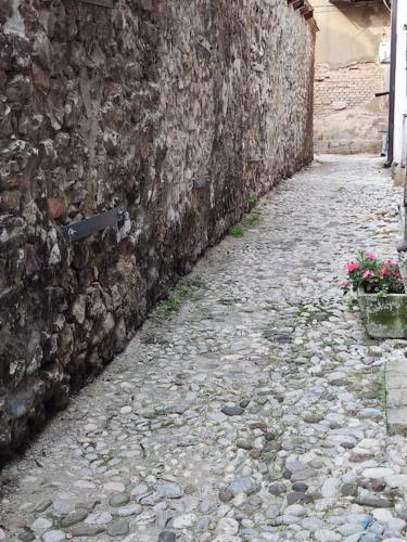 a stone alley next to a stone wall with flowers at Bascarsija apartment B-Home Old Town Sarajevo in Sarajevo