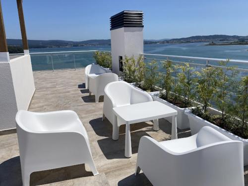 een rij witte stoelen en tafels op een patio bij Apartamentos O Grove Awa Bay in O Grove