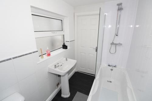 a white bathroom with a sink and a bath tub at Belfast Cozy Home in Belfast
