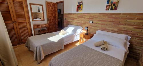1 dormitorio con 2 camas y pared de ladrillo en Villa Clementina, en Es Pujols
